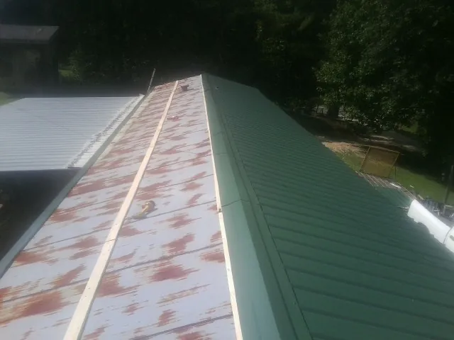 Old rusted panels beside newly installed green metal roofing — Wind Damage Roof Repair by Roofing Brothers in Boston