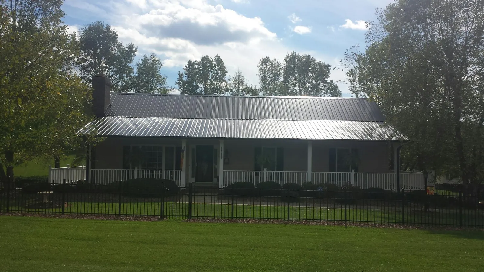Gray metal roof on a brick ranch with a full width front porch — Gutter Guard Installation work by our crew in Boston